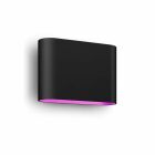 En svart vggmonterad armatur med nedtriktat rosa sken visas i nrbild.