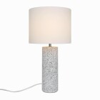 En vit bordslampa med cylindrisk tygsk�rm och dekorativ, strukturerad lampfot st�r t�nd och sprider ett mjukt, behagligt ljus som passar i moderna hem, en stilren belysningsl�sning fr�n Elbutik.se.