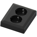 En svart tv�v�gsuttag med jordade uttag �r placerat i fokus och visas snett uppifr�n, vilket framh�ver dess matta finish och robusta konstruktion. Produkten, som erbjuds av Elbutik.se, �r anpassad f�r s�ker elinstallation i moderna hemmilj�er.