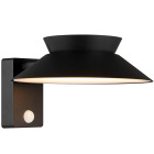 En v�ggmonterad utomhuslampa i svart metall med bred, vinklad sk�rm sprider ett mjukt ned�triktat ljus. Den integrerade sensorn p� f�stet m�jligg�r automatisk aktivering, och hos Elbutik.se finns denna praktiska belysning f�r entr�er och fasader