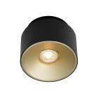 Spotlampan Torone i svart cylindrisk design sitter monterad i taket och riktar ett varmt, fokuserat ljus ned�t i en minimalistisk hallmilj� med b�nk och dekor, visad p� produktsida; finns hos Elbutik.se.