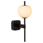V�gglampa med svart v�ggf�ste, vertikal svart st�ng och rund opalvit glaskupa som lyser med varmt sken.