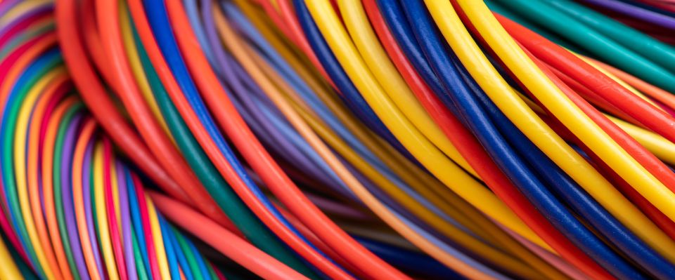 Ett virrvarr av färgglada elkablar i närbild visar olika isoleringsfärger för enkel identifiering vid eldragning. Elbutik.se erbjuder dessa kablar för säkra och tydligt organiserade elinstallationer.