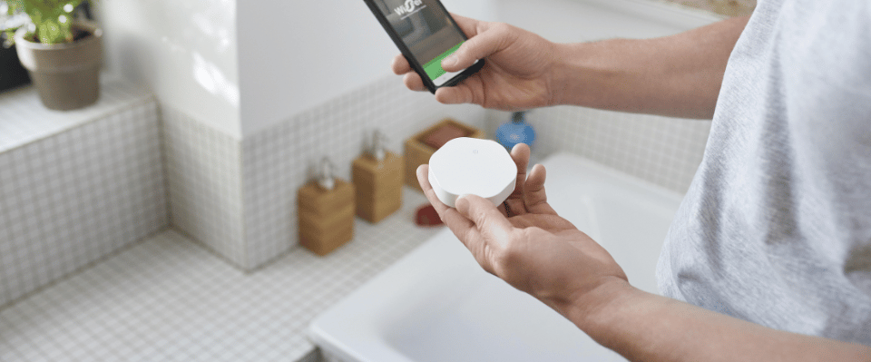 Elbutik.se erbjuder ett vitt vattenlarm som h&aring;lls i handen medan det ansluts via en mobilapp i ett kaklat badrum, utformat f&ouml;r att snabbt varna vid l&auml;ckage n&auml;ra badkar och r&ouml;r.